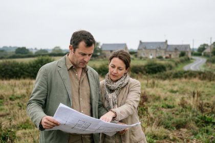 Couple examinant des plans de construction sur un terrain à bâtir en périphérie de Rennes