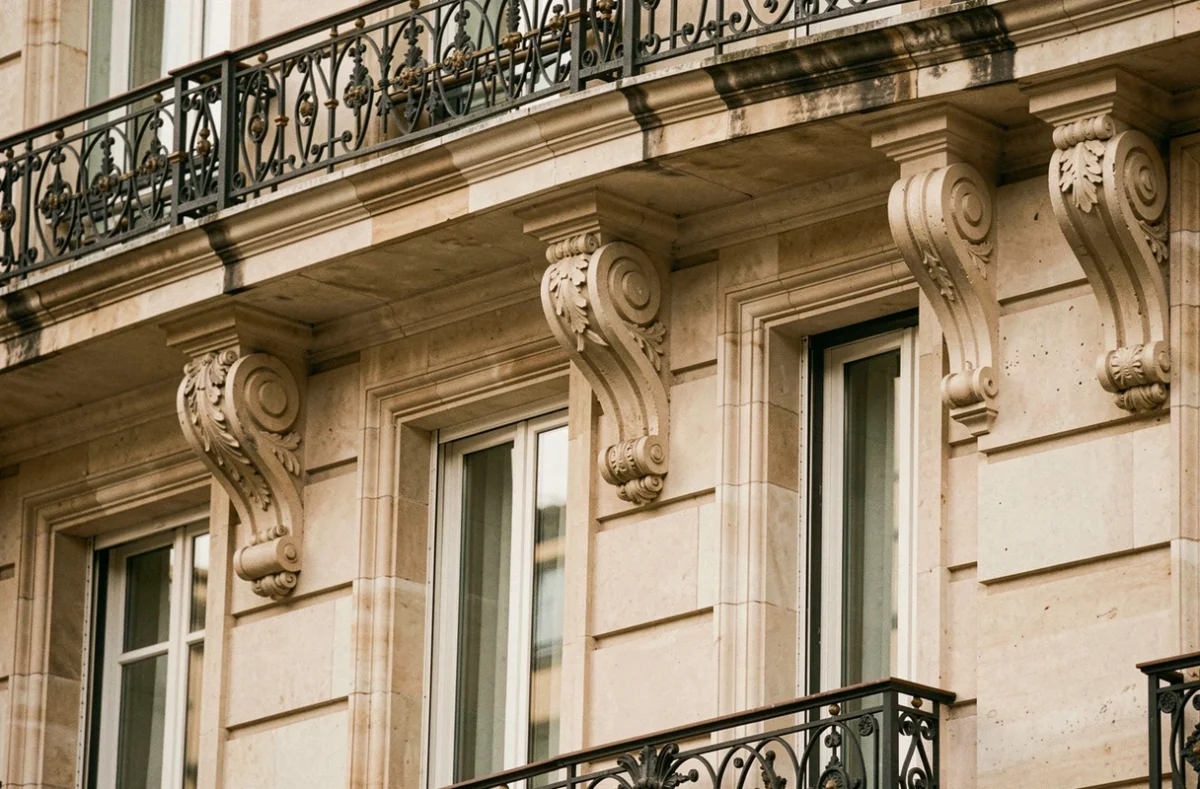 Détail architectural d'une corniche haussmannienne avec consoles sculptées et balcon en fer forgé