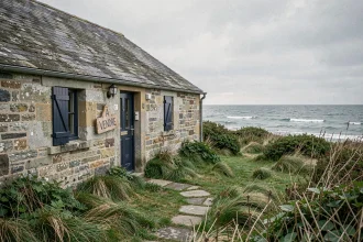 Maison de pêcheur en pierre de granit à vendre en Bretagne avec vue mer et volets bleus délavés